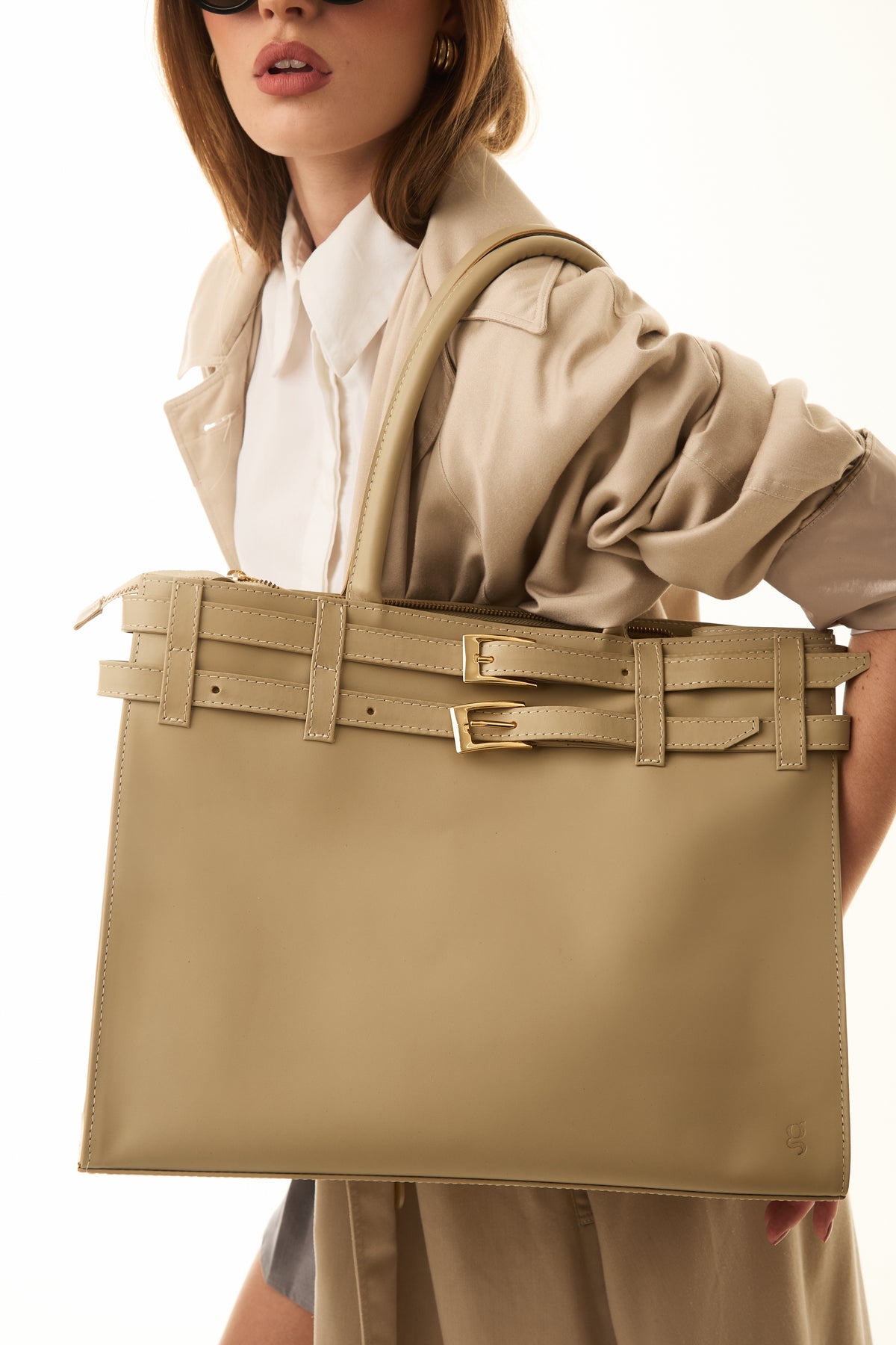 Mulher segurando bolsa de couro bege com fivelas da Fygô